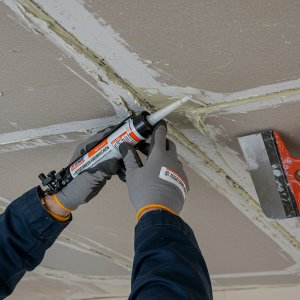 Sealing all joints and seams with sealant and putty for ceiling soundproofing.