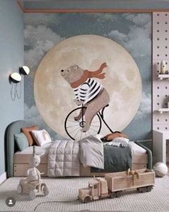 Child's bedroom wallpaper mural depicting a large pale full moon, brown bear with glittery fur riding a bicycle.
